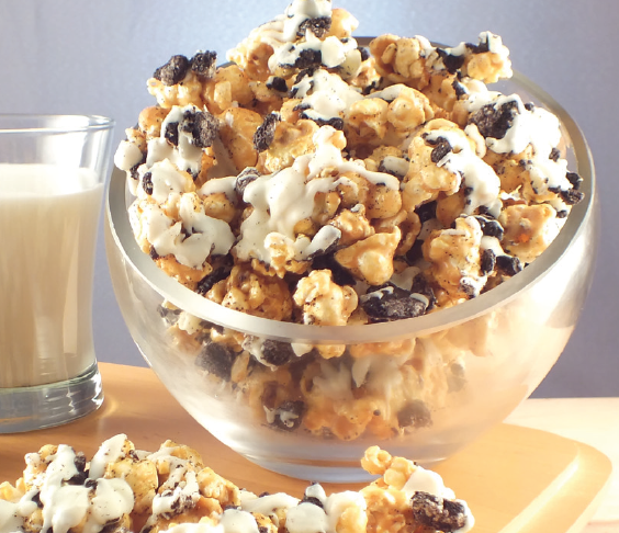 A glass of milk next to a bowl of Cookies and Cream popcorn, a great choice for a popcorn fundraiser.